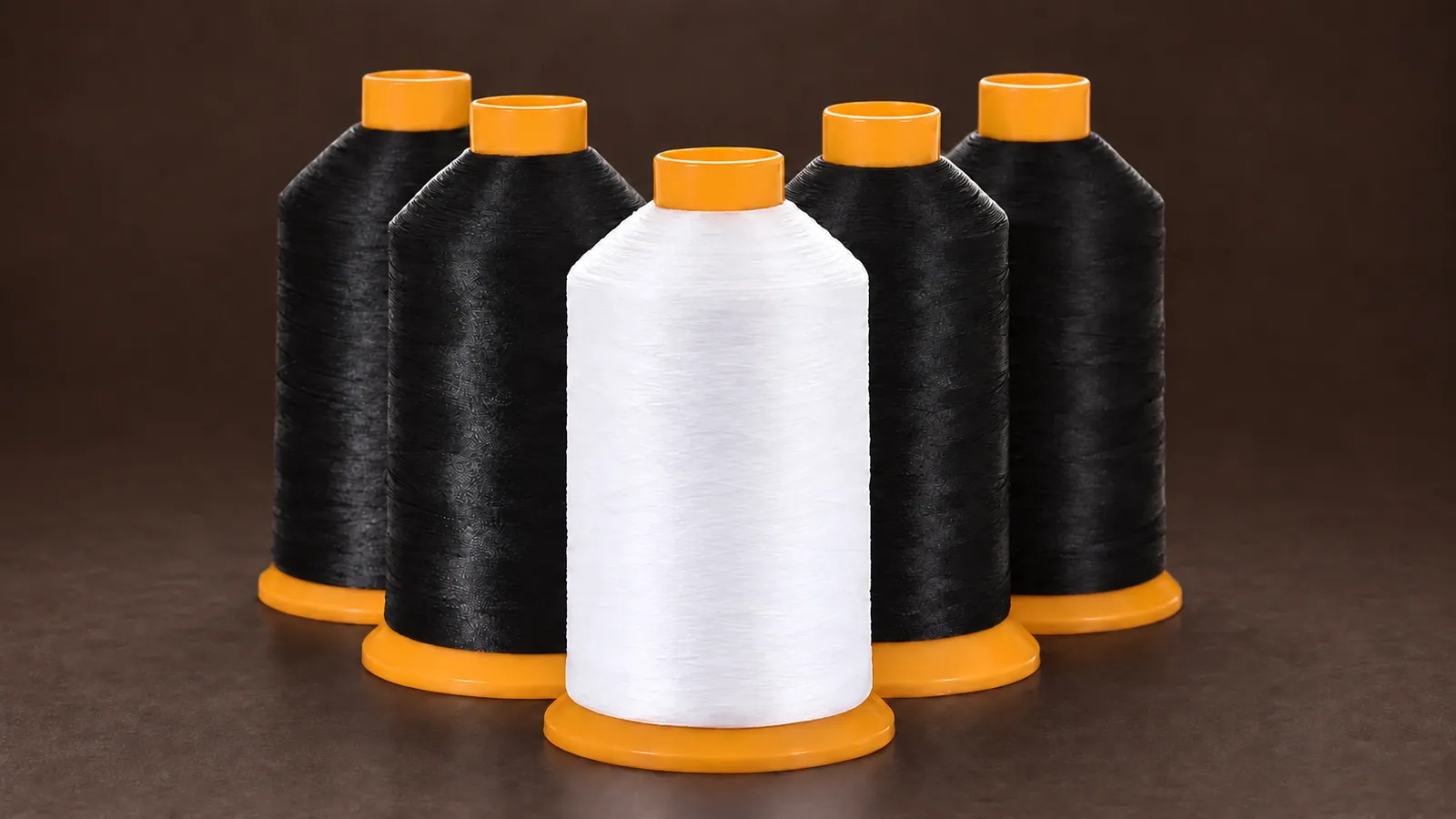 Nylon Sewing Thread. Four black and one white thread cone with orange cores; label removed. Source-based AI-edited visualization.